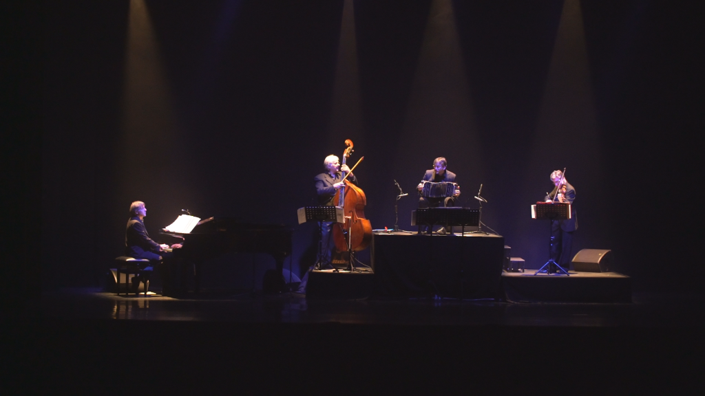 Músicos, no palco, executando trilha sonora de Tango Genuine